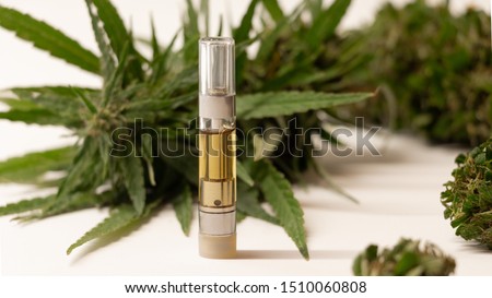 Hemp derived CBD oil infused vape smoking refill cartridge on white background with large hemp flower buds. Generic product image. Popular cigarette smoking substitute.