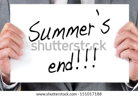 a man in suit holding a blackboard with the sentence summers end written in it