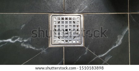 Metal drain hole in the tiled floor of a shower. Clean tile floor of the modern bathroom in urban town.