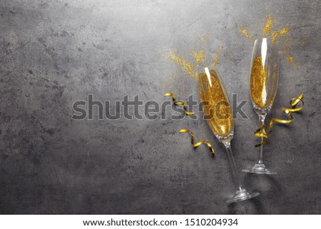 Flat lay composition with champagne glasses for celebration on grey stone background. Space for text