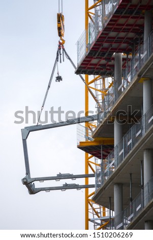 Crane hoisting block with hook on steel chain on the steel rope lift the huge steel beams. Loading\unloading of building materials on construction building site.