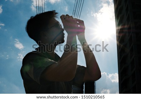 An Asian tourist taking a photo with the cityscape background. [silhouette]