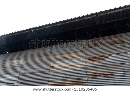 Raining over grunge rusty old zinc sheet warehouse. 