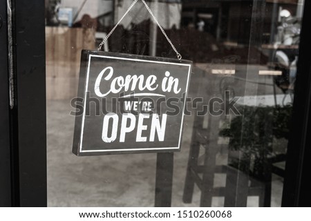 Come in we're open, vintage black retro sign on a dirty glass door.