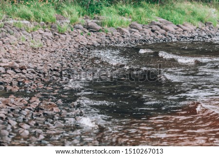 Stone river bank. Beautiful beach covered with large stones. Photo background with shore with copyspace