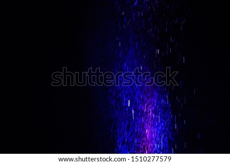 Colorful powder/particles fly after being exploded against black background