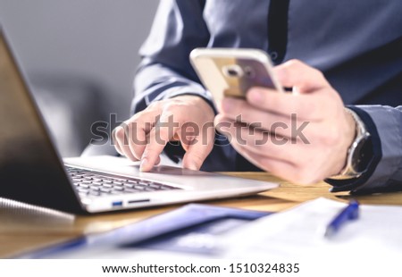 Multitasking and mobile technology. Busy workaholic business man using phone and laptop. Entrepreneur working hard with smartphone and computer. Efficient worker or executive manager in office. Royalty-Free Stock Photo #1510324835