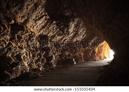 Empty road goes through the cave with glowing end