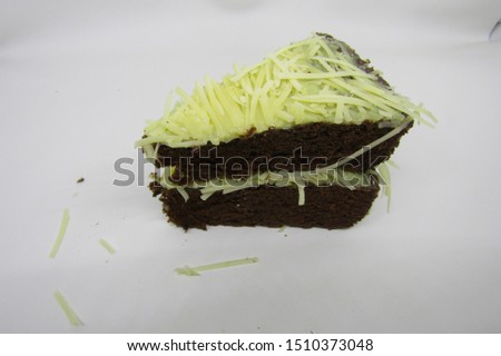 Close up of bronies cake cut slices with grated cheddar cheese topping on top. Triangle shape delicious taste on white plate. Appetizer gourmet dark brown color pieces. Flat lay top view for advertise
