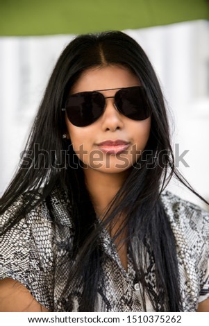 Fashion portrait of an indian stylish woman in sunglasses, long black hair and snake jumpsuit