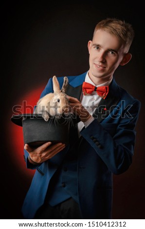 a young guy magician illusionist holding a hat with a rabbit