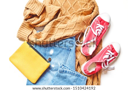Flat lay photo modern fashion outfit. Brown woolen sweater, light blue jeans, yellow purse and red gumshoes