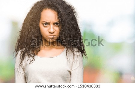 Young beautiful girl with curly hair wearing casual sweater skeptic and nervous, frowning upset because of problem. Negative person.