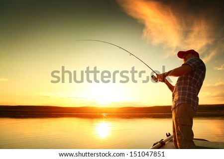 Young man fishing on a lake from the boat at sunset Royalty-Free Stock Photo #151047851