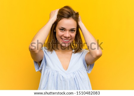 Young pretty young woman laughs joyfully keeping hands on head. Happiness concept.