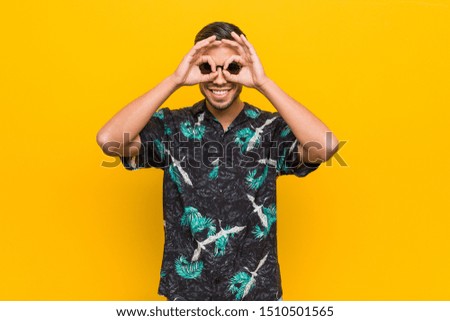Young filipino man wearing summer clothes showing okay sign over eyes