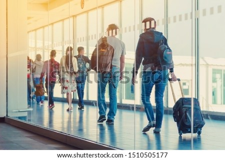 Back view of passengers and traveling luggage walking the airplane boarding corridor from the terminal to the plane. Royalty-Free Stock Photo #1510505177