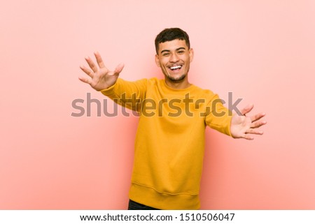 Young hispanic man feels confident giving a hug to the camera.