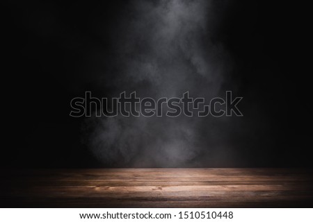 empty wooden table with smoke float up on dark background Royalty-Free Stock Photo #1510510448