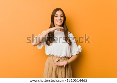 Young caucasian woman holding something with both hands, product presentation.