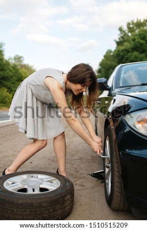 Car breakdown, young woman puts the spare tyre