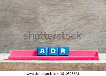Tile letter on red rack in word ADR (Abbreviation of adverse drug reaction) on wood background