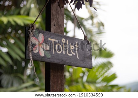 wooden toilet sign with trees background