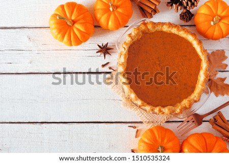 Homemade autumn pumpkin pie corner border. Top view table scene over a white wood background with copy space.