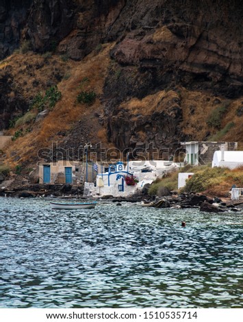 A rowing boat sits moored in front of a tiny Greek orthodox chapel on one of the small islands of Santorini