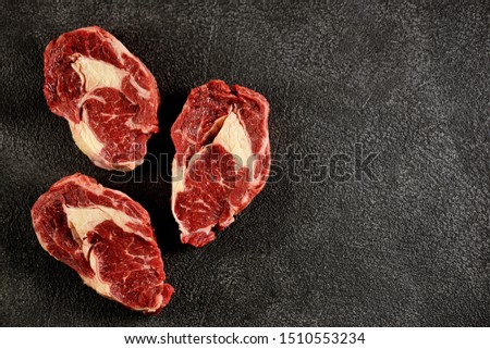 Three raw fresh beef steaks rib eye on a black background. 