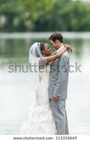 Newly wed couple embracing next to a lake