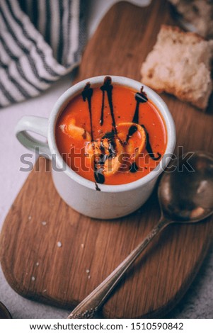 Autumn red tomato cream soup with homemade cheese tortellini and topped with balsamic reduction. Soup bowl in rustic style.