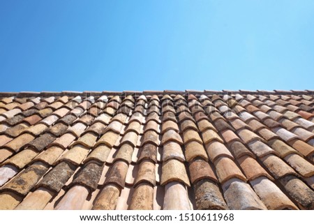 View of old roof tiles and blue sky on sunny day