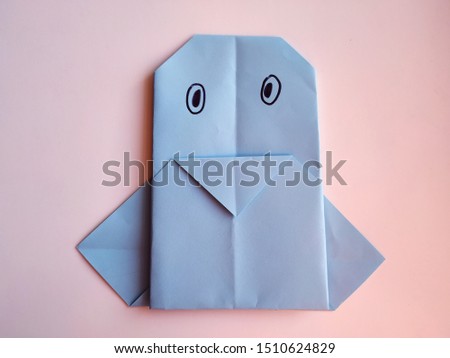 Origami blue penguin on a light background. Colorful paper crafts.