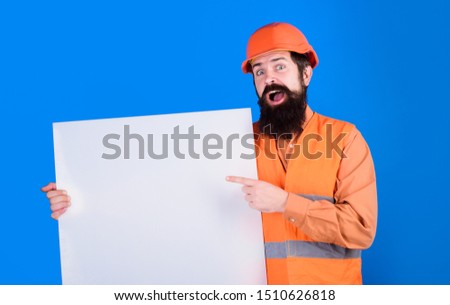 Builder with blank board. Repairman in protective helmet holds empty board with space for text. Man builder holds advertising banner, billboard, sign board. Construction worker, engineer, architect.