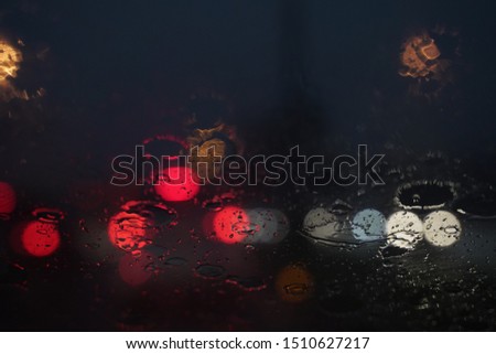 Rain drop reflect at night. Rain drops on car window with road light bokeh, City life in night in rainy season abstract background,water drop on the glass, night storm raining car driving concept.