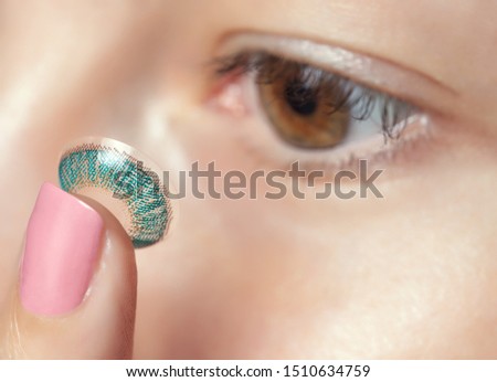 One woman holds a blue contact lens on her finger. Eye care and the choice between the means to improve vision.
