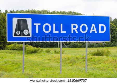 Road sign Toll road against sky and forest