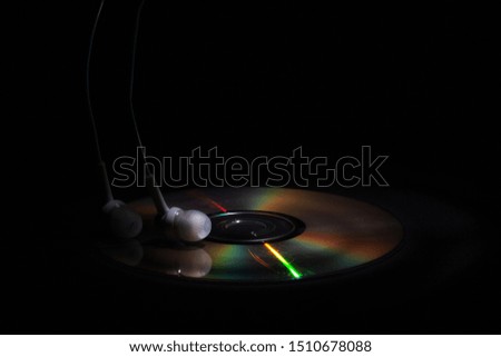 cd compact disk and white headphones on a dark background. concept: listen to music  close-up