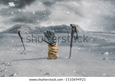 Hiker stretching out his snow covered hand next to trekking poles to signal help because of snow avalanche . Danger extreme concept Royalty-Free Stock Photo #1510694921