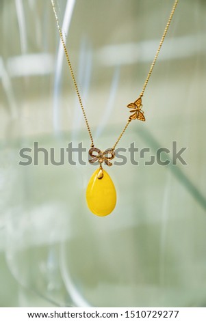 Golden necklace with amber and small diamonds on a glass shelf. Close up.