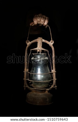 Hand holds an old gas lamp on a black background