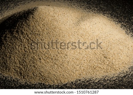 A pile of sand on a black reflective surface