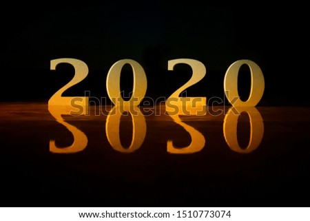 Happy New Year 2020 wooden number with light thru with reflections on the floor in gold colour on background 