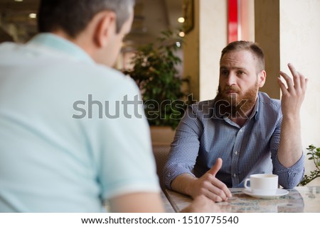 two men discussing difficult issues with emotions during coffee break in cafe talking about problems