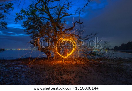 burning steel wool under mangrove tree in heart shape in twilight at Klong Mudong Phuket Thailand.