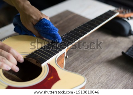 Guitar repairer is cleaning acoustic guitar, Clean cloth to wipe the fretboard, Close-up Royalty-Free Stock Photo #1510810046