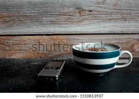 Coffee and phone on wood background.