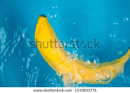 Banana falling into water on blue background