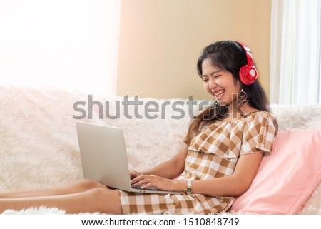 Portrait of Young Asian woman enjoy listening to music with headphones and using laptop, happy and relaxing time